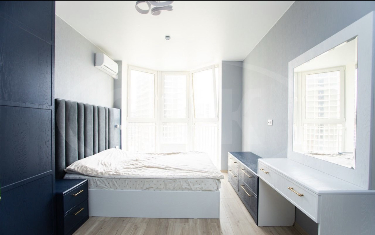 Стильная спальня в синем цвете в сочетании с белым. Кровать с мягким изголовьем.